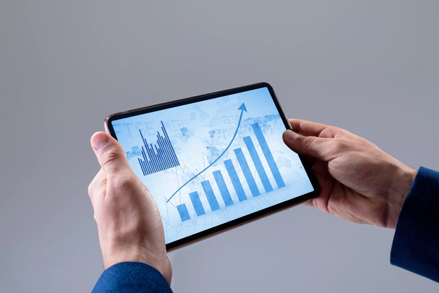 Hands holding a tablet displaying a rising business growth chart